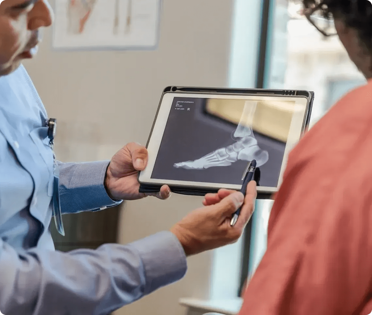 Doctor explaining foot X-ray on tablet